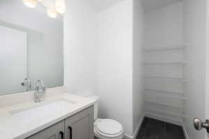 Bathroom with toilet, tile patterned floors, and vanity