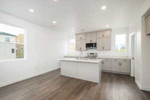 Kitchen featuring dark hardwood / wood-style floors, appliances with stainless steel finishes, an island with sink, gray cabinets, and sink