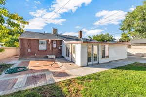 Rear view of property featuring a lawn and a patio area