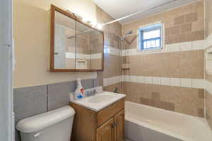 Full bathroom with toilet, vanity, and tiled shower / bath