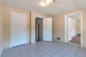 Unfurnished bedroom featuring light tile patterned flooring, a closet, and vaulted ceiling