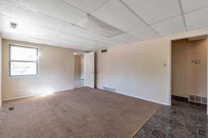 Tiled empty room featuring a drop ceiling