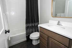 Full bathroom featuring shower / bath combo with shower curtain, vanity, tile patterned flooring, and toilet