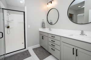 Bathroom featuring double vanity, tile patterned flooring, and a shower with shower door