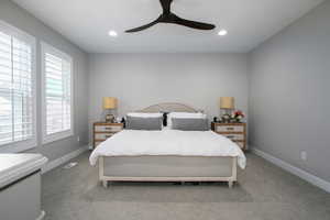 Carpeted bedroom featuring ceiling fan and multiple windows