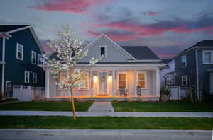 View of front of house with covered porch and a yard