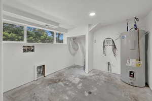 Interior space with electric water heater, a textured ceiling, and hookup for a washing machine