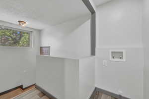 Washroom featuring wood-type flooring, a textured ceiling, and washer hookup