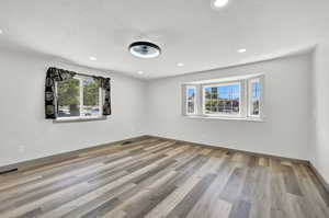 Empty room with hardwood / wood-style floors and a textured ceiling