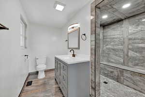 Bathroom with tiled shower, toilet, vanity, and tile patterned flooring