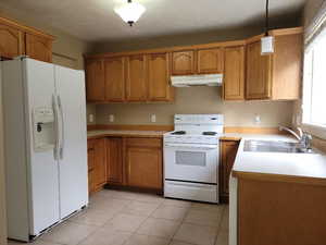 Kitchen with pendant lighting, white appliances, sink, and light tile patterned floors