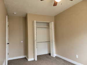 Unfurnished bedroom with ceiling fan, a closet, and light carpet