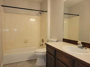 Full bathroom with tile patterned flooring, vanity, shower / bath combination, and toilet