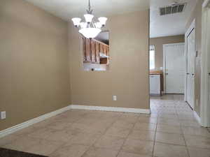 Unfurnished room with a notable chandelier and light tile patterned flooring