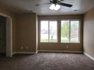 Carpeted empty room featuring ceiling fan and a textured ceiling