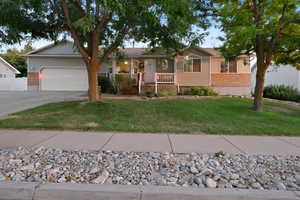 Single story home featuring a garage, a porch, and a front lawn