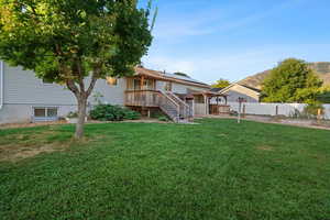 Back of house with a deck and a lawn