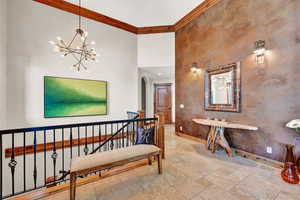 Interior space featuring a towering ceiling, ornamental molding, a chandelier, and light tile patterned floors