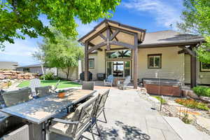 Rear view of property with a hot tub and a patio area