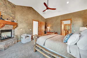 Bedroom with a fireplace, ceiling fan, high vaulted ceiling, and carpet floors