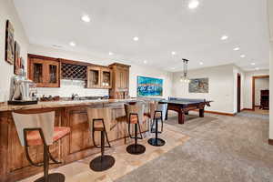 Interior space with sink, decorative light fixtures, light stone counters, pool table, and light carpet