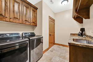 Laundry area with sink, light tile patterned floors, cabinets, and washer and dryer