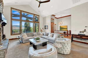 Living room with ceiling fan with notable chandelier and high vaulted ceiling