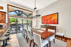 Dining space featuring high vaulted ceiling and light hardwood / wood-style flooring