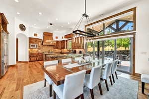 Dining area with light hardwood / wood-style floors, a towering ceiling, and sink