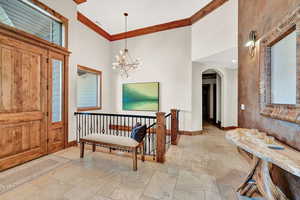 Foyer entrance featuring light tile patterned flooring, a towering ceiling, and a chandelier