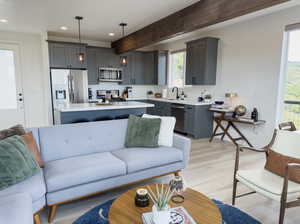 Living room featuring sink, light wood-type flooring, and beamed ceiling