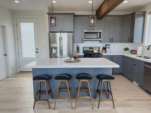 Kitchen with light wood-type flooring, stainless steel appliances, sink, and beam ceiling