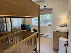 Bedroom featuring baseboard heating, a crib, and carpet floors