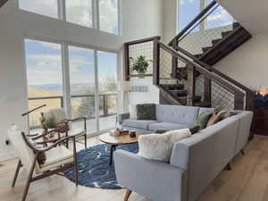 Living room with a towering ceiling, light hardwood / wood-style flooring, and a healthy amount of sunlight