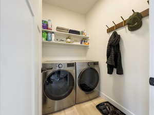 Washroom featuring washing machine and dryer and light hardwood / wood-style floors