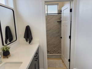 Bathroom with tiled shower, tile patterned floors, and dual bowl vanity