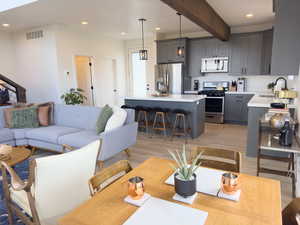 Living room with beamed ceiling, light wood-type flooring, and sink