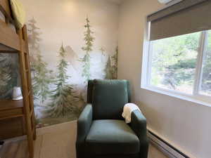 Sitting room with a baseboard heating unit and hardwood / wood-style flooring