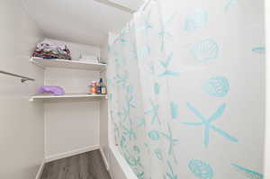 Bathroom featuring shower / tub combo and wood-type flooring