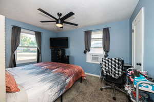 Bedroom featuring ceiling fan, cooling unit, a textured ceiling, and carpet flooring