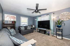 Carpeted living room with a textured ceiling and ceiling fan