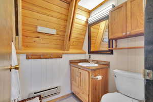 Bathroom featuring a baseboard heating unit, toilet, and vanity