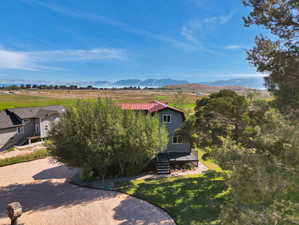 View of front of property with a deck with mountain view and a front lawn