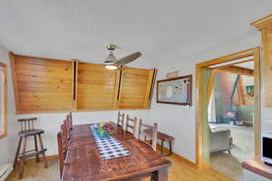 Dining space with a textured ceiling, light hardwood / wood-style flooring, ceiling fan, and a wood stove