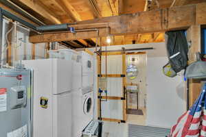 Interior space featuring stacked washer and clothes dryer, tile patterned flooring, sink, electric water heater, and white fridge