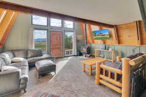 Carpeted living room featuring wooden walls and a wood stove