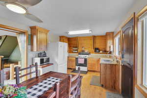 Kitchen with wood walls, sink, white appliances, light stone countertops, and light hardwood / wood-style floors