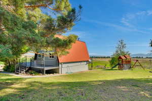 View of yard featuring a rural view, a playground, and a deck