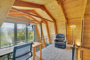 Sitting room with wood walls, a mountain view, vaulted ceiling with beams, and wooden ceiling