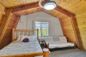 Bedroom featuring vaulted ceiling with beams, carpet, and wood ceiling